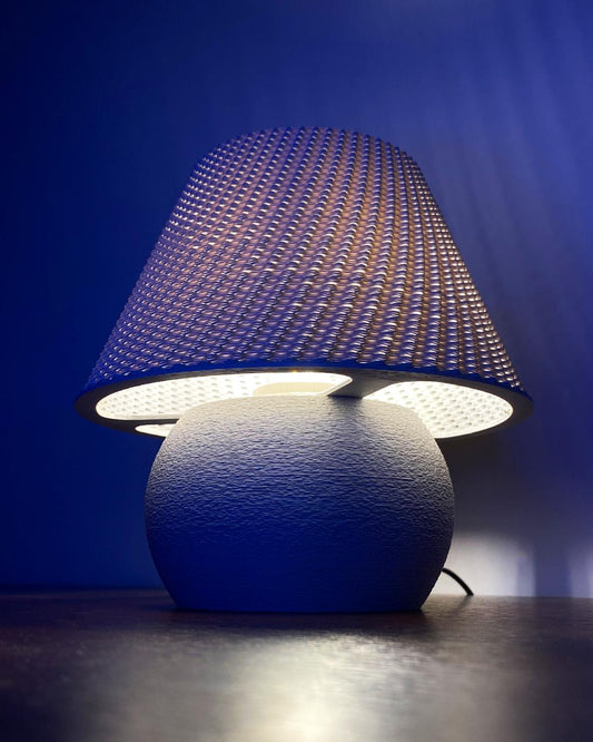 Blue textured table lamp with a unique shade against a dark background