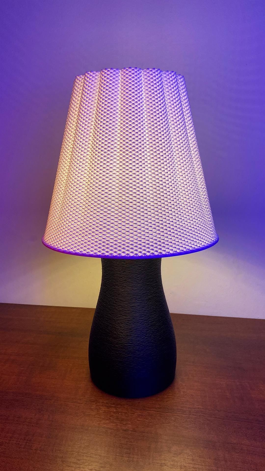 Table lamp with a textured white shade and black base on a wooden surface.