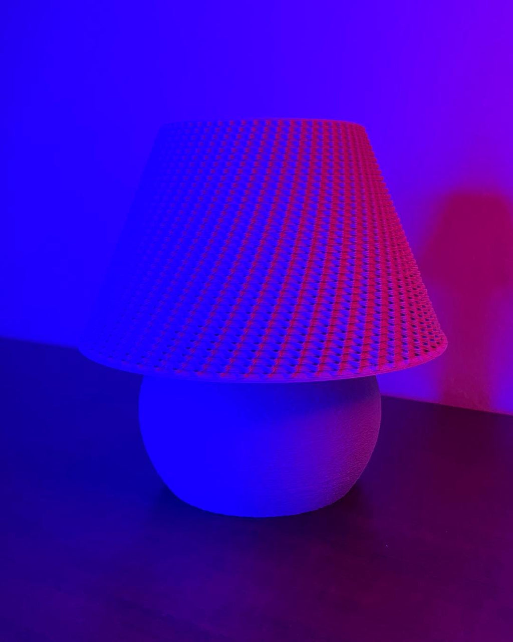 Lamp with a textured red shade and white base against a dark background