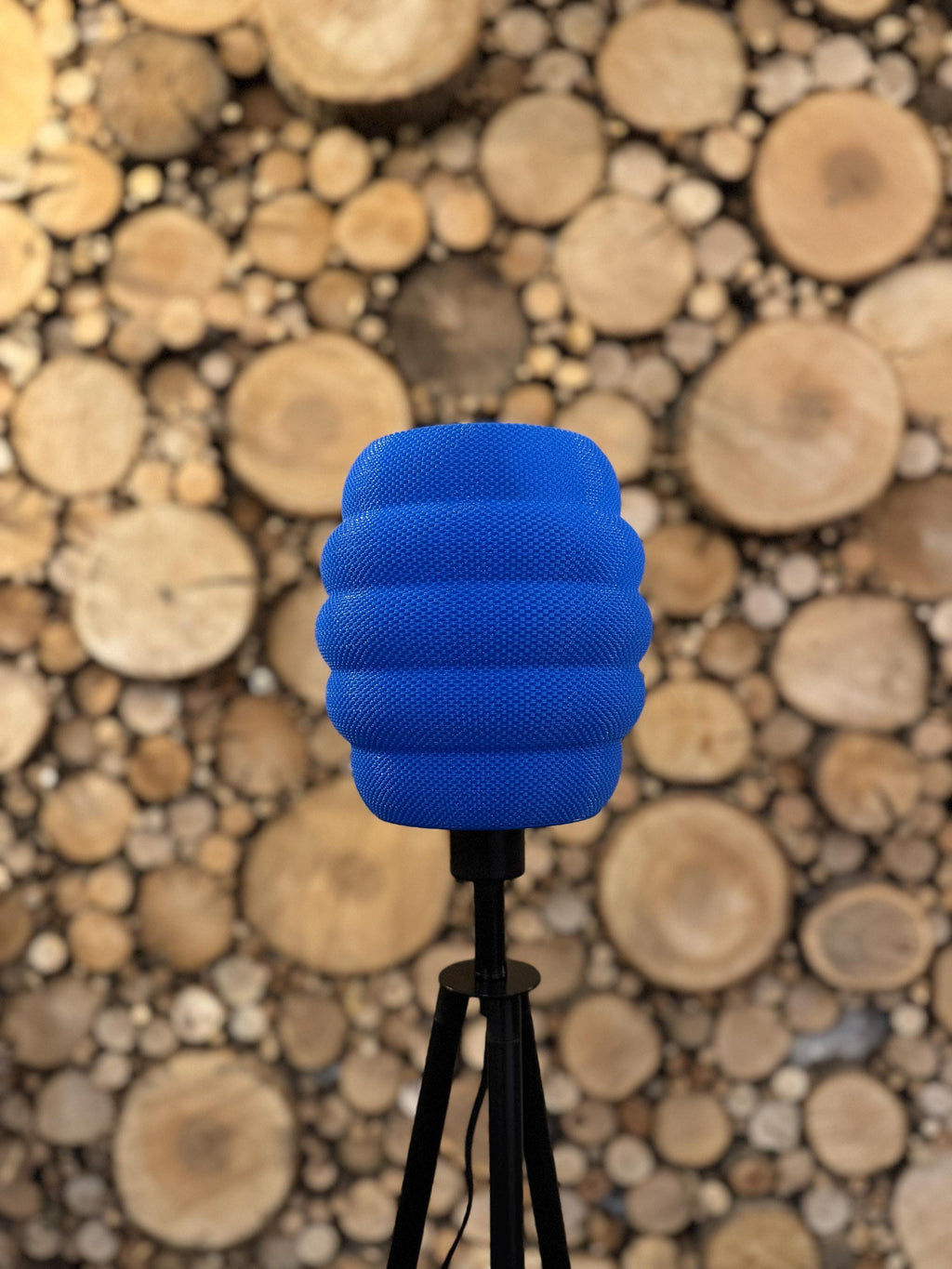 Blue textured object on a stand with a wooden log wall background