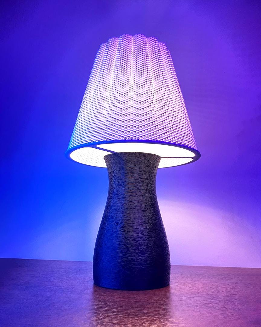 Table lamp with textured base and colorful shade on a reflective surface