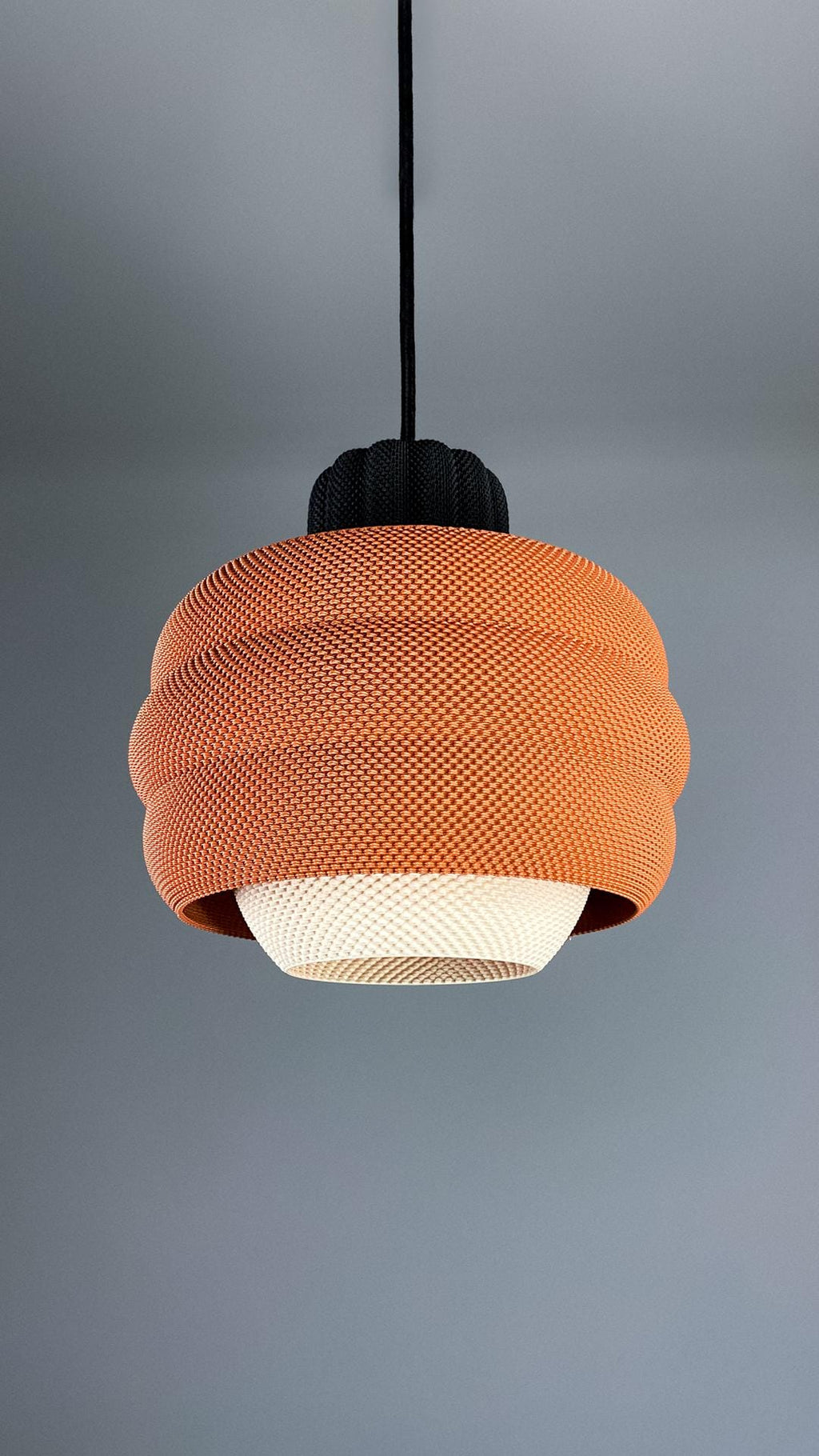Orange pendant light with a textured design on a gray background