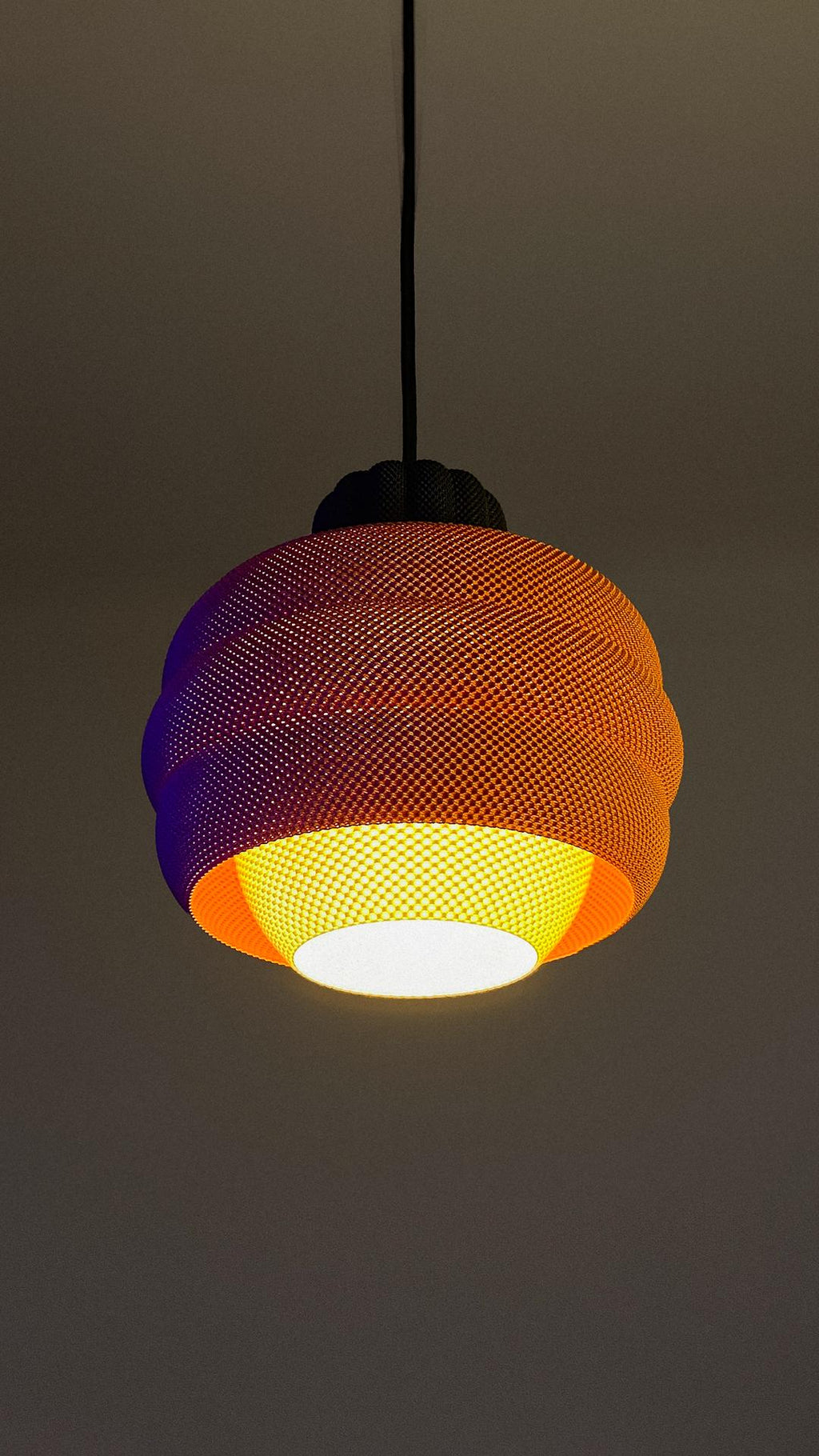 Colorful woven pendant light against a dark background