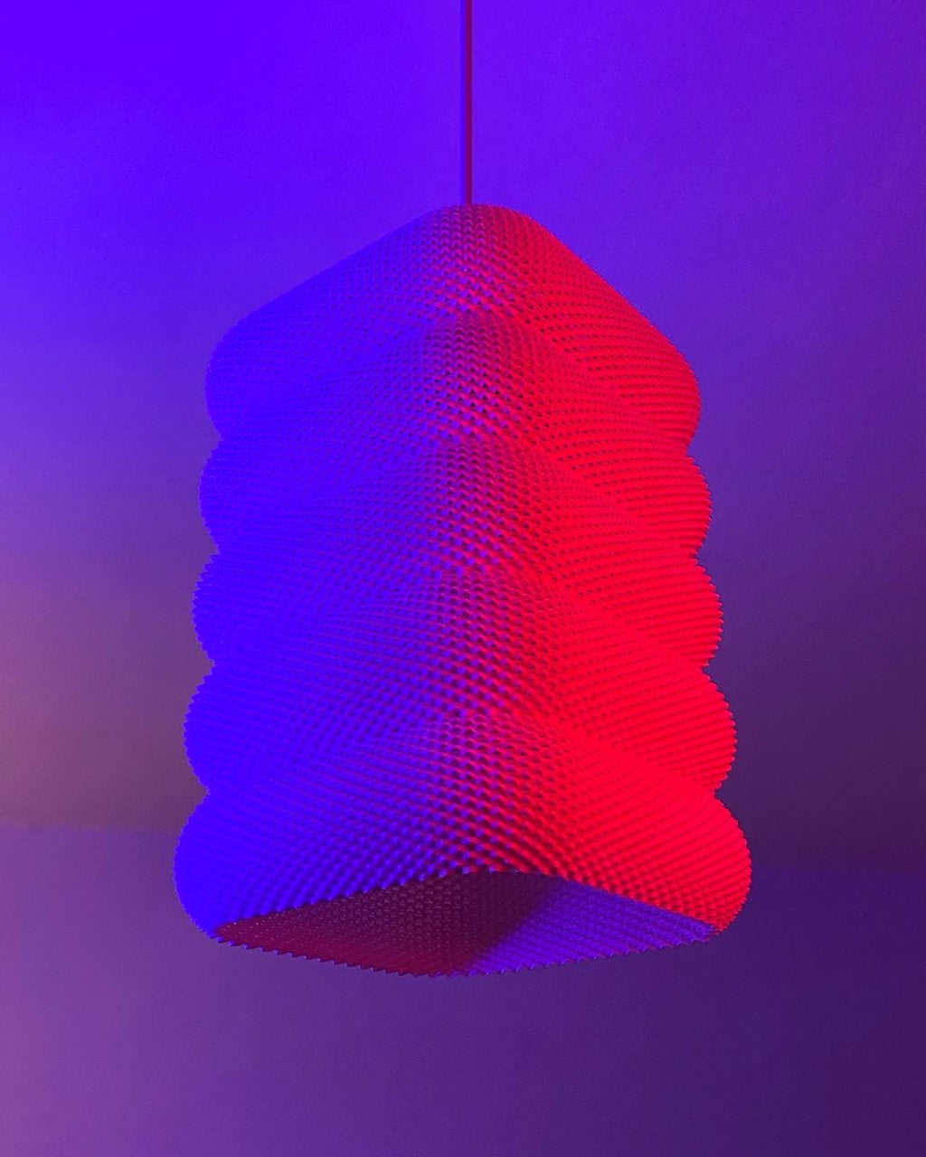 Geometric pendant light with red and blue gradient on a purple background