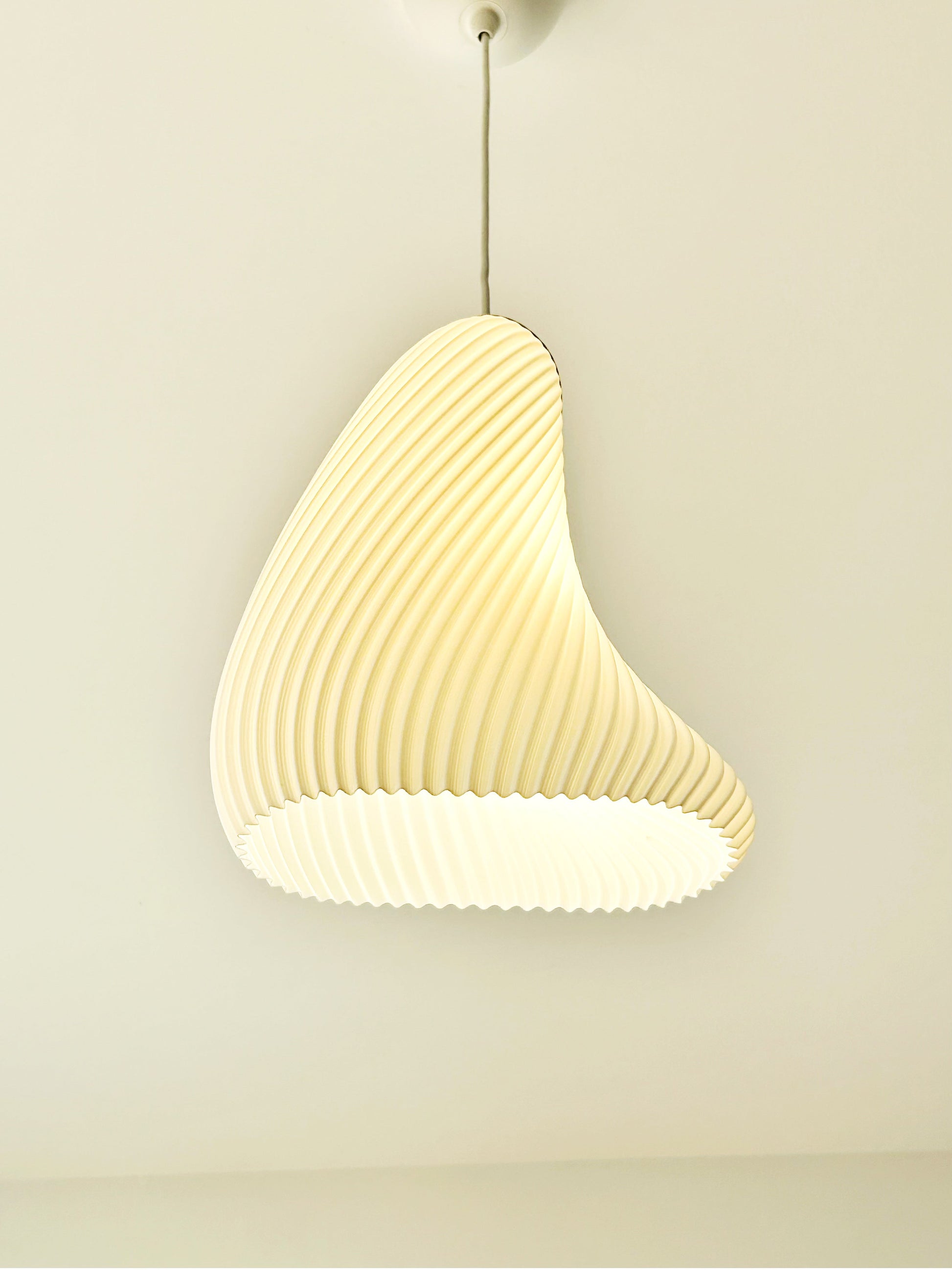 Beige pendant light hanging against a plain wall