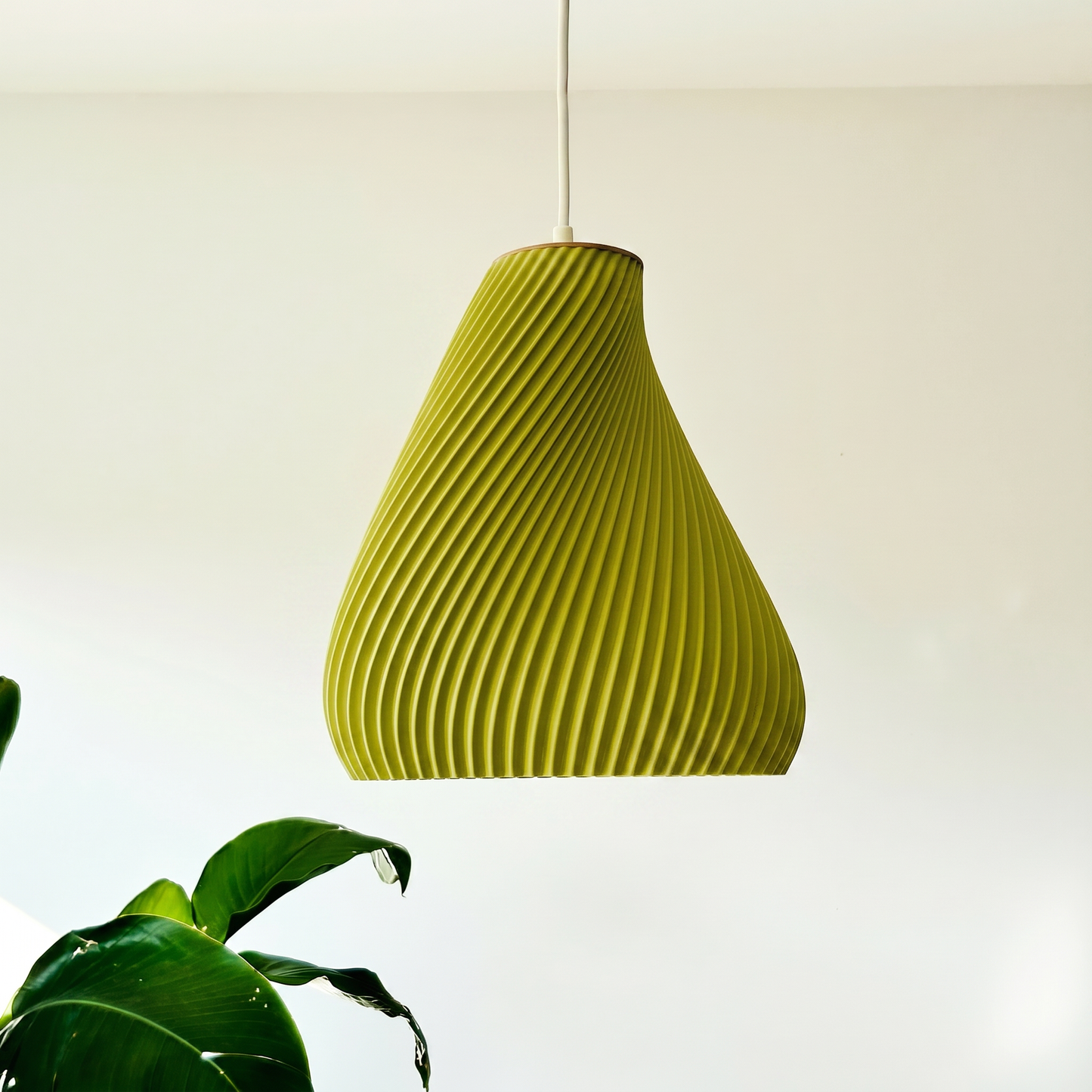 Green textured pendant light hanging against a plain background