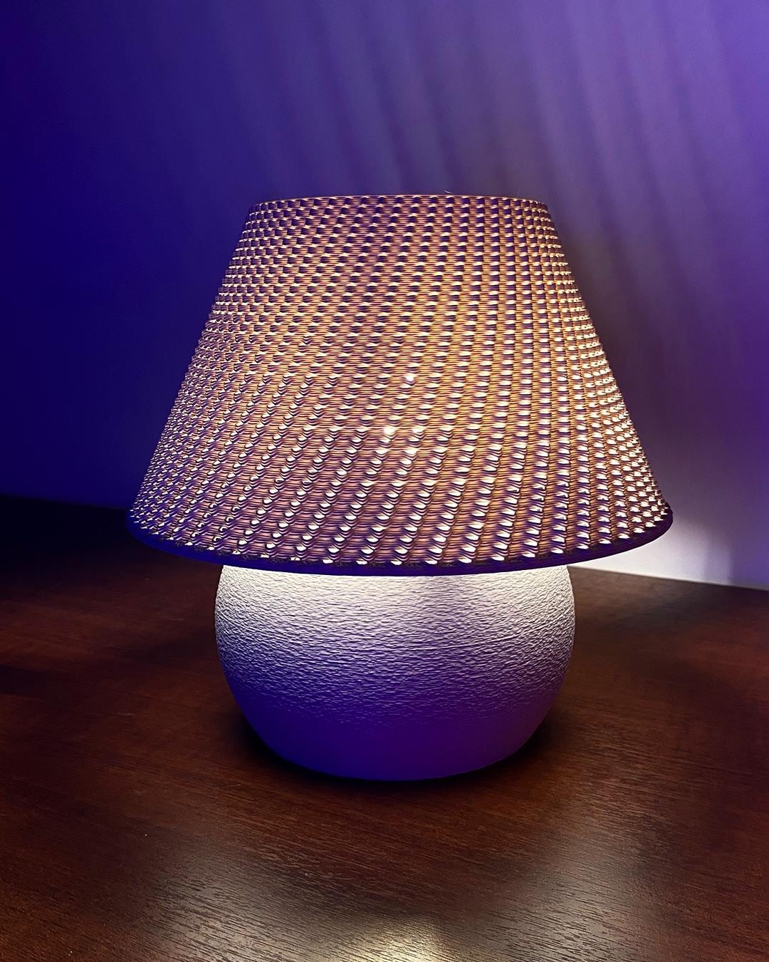 Table lamp with woven shade on a wooden surface against a dark background
