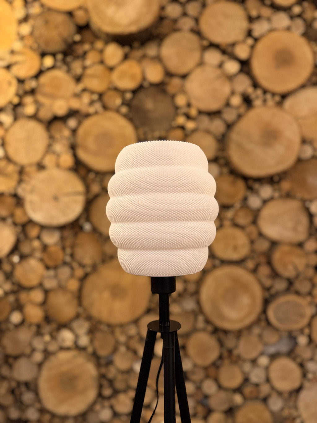 White textured lampshade on a black stand against a wooden background
