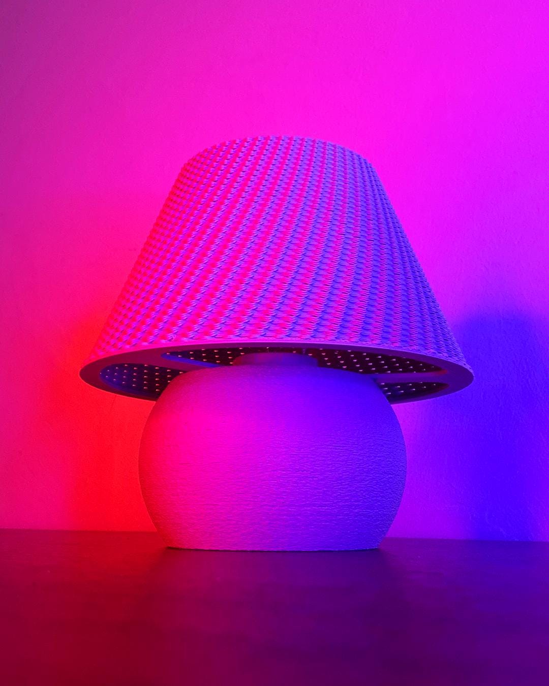 Decorative lamp with a textured base and colorful LED shade against a pink and purple gradient background.