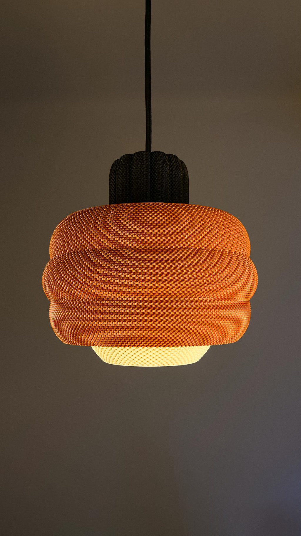 Orange textured pendant light against a dark background