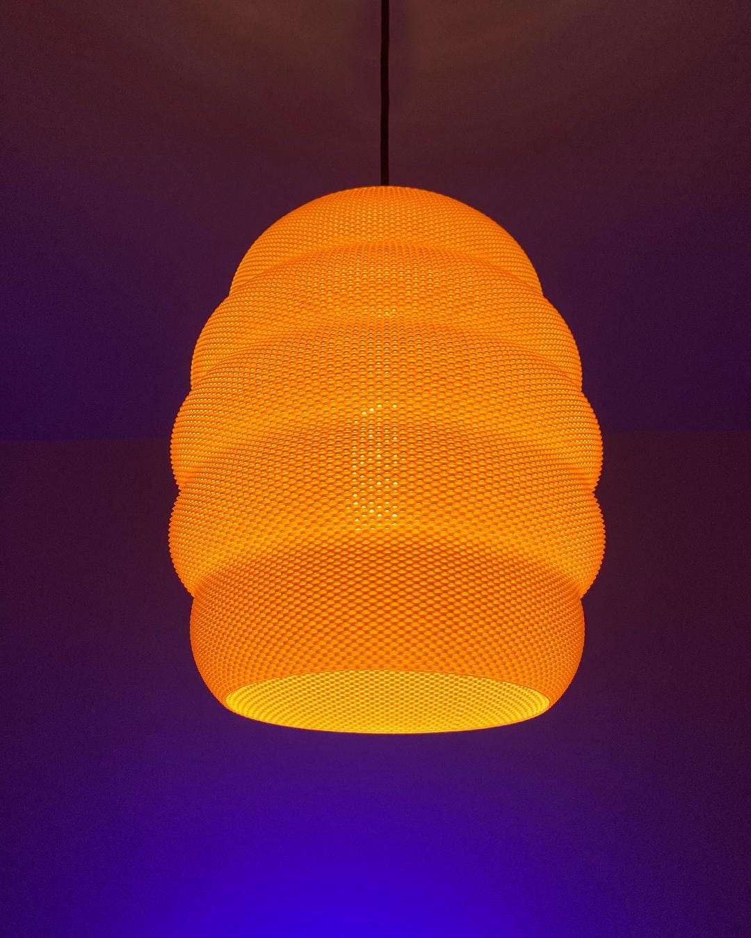 Orange beehive woven pendant light against a dark background