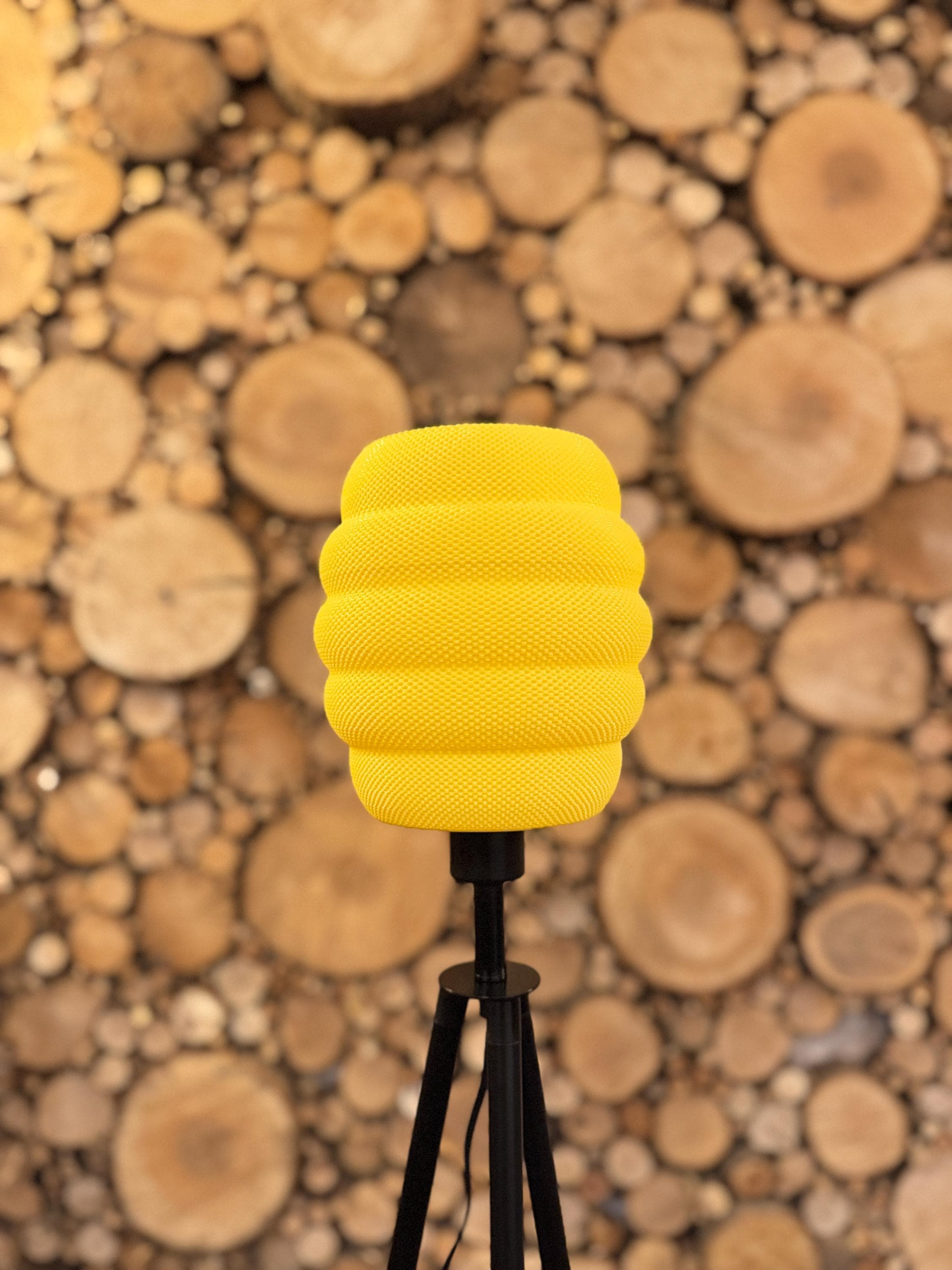 Yellow textured lamp on a stand with a wooden log wall background